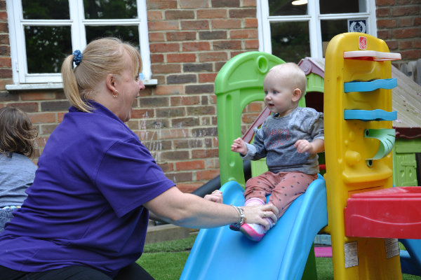 Nursery Practitioner with child on slide
